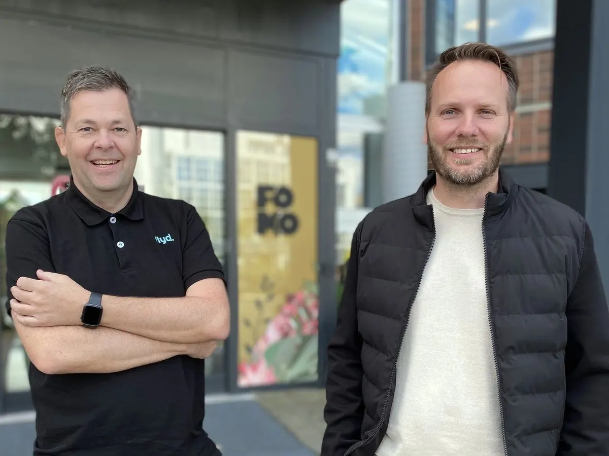 To Flyd-kolleger smiler foran inngangen til FOMO-bygget på Forus